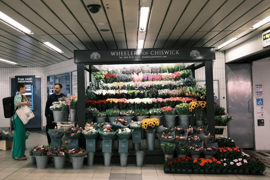 A flower display at Wheeler of Chiswick, situated in the Basildon underground station, featuring an array of fresh flowers including roses, daisies, and tulips in vibrant colours such as pink, white,